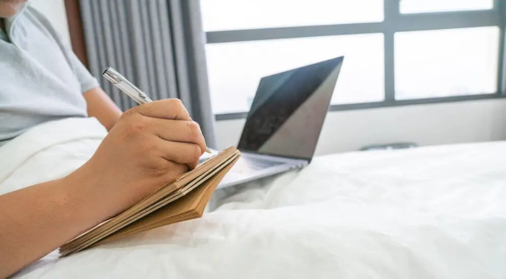 Person completing a structured sleep diary journal at their desk